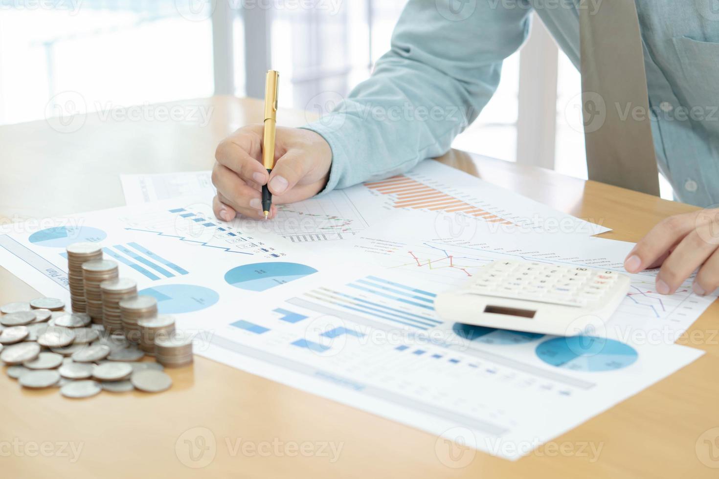hombre de negocios usando calculadora y tableta con monedas apiladas dispuestas foto