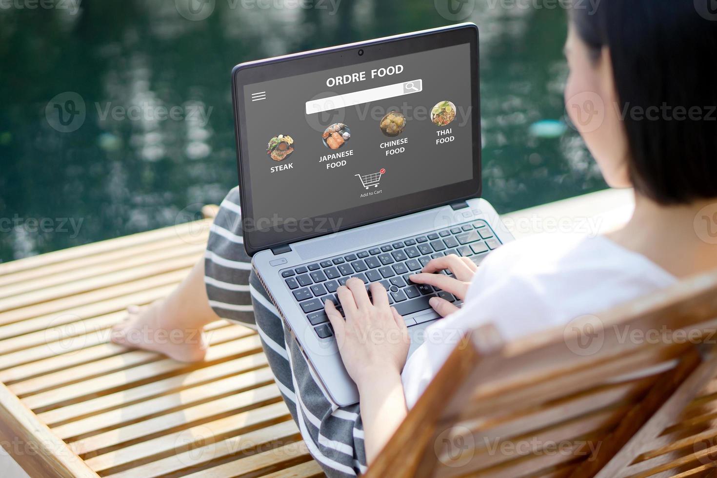cerrar una mujer sentada y pedir comida en línea en una computadora portátil foto