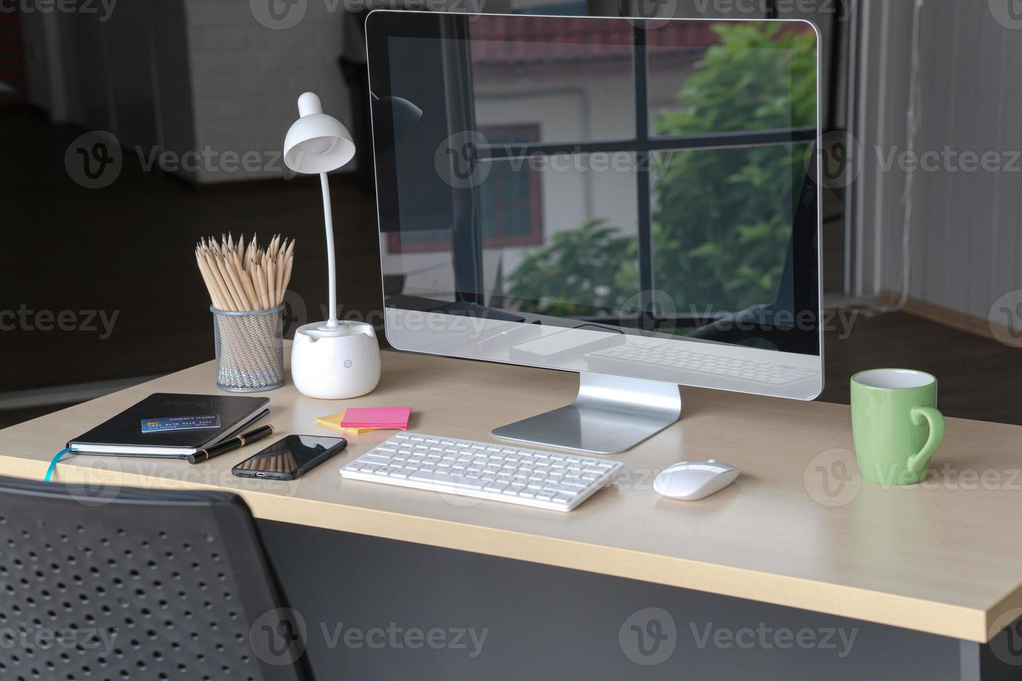 Business and workplace concept. Cup of hot coffee on work desk with computer keyboard Mobile and papers graphs in office working room. photo