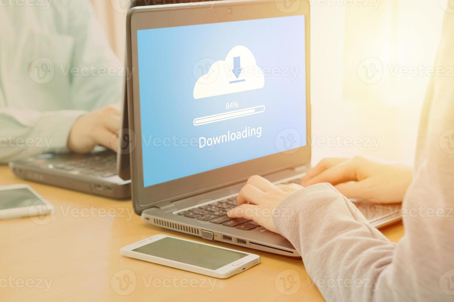 Young employee looking at computer monitor to cloud downloading working day in office photo