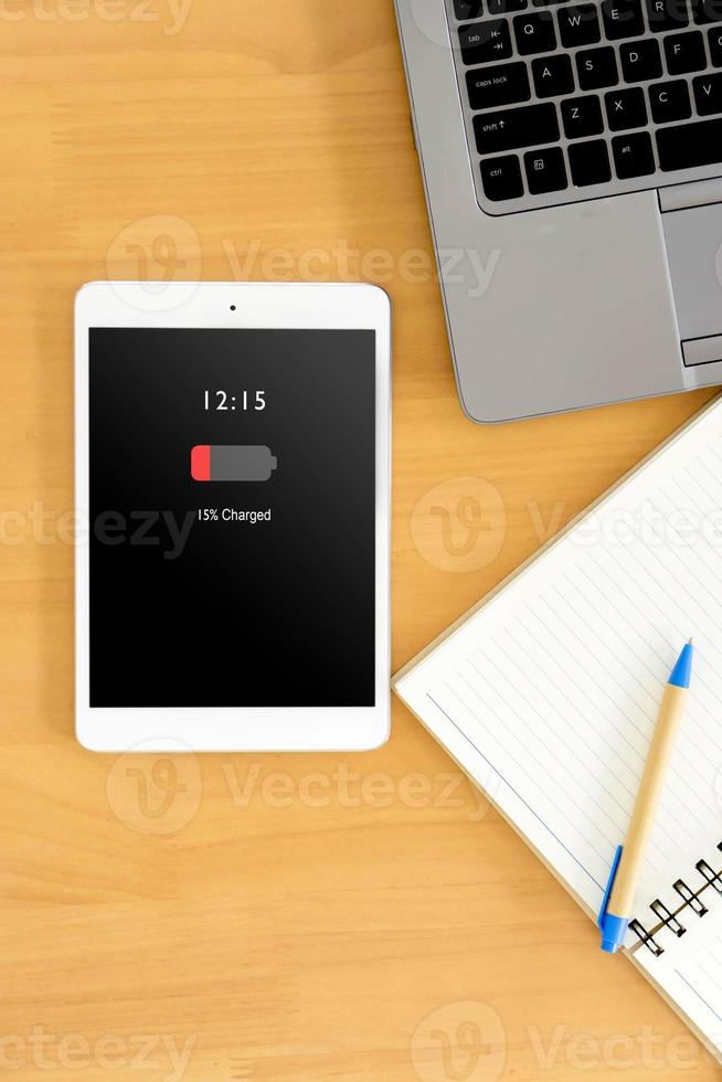 top view of business workspace to mobile phone with low charged battery screen, notebook and female hands typing on keyboard photo