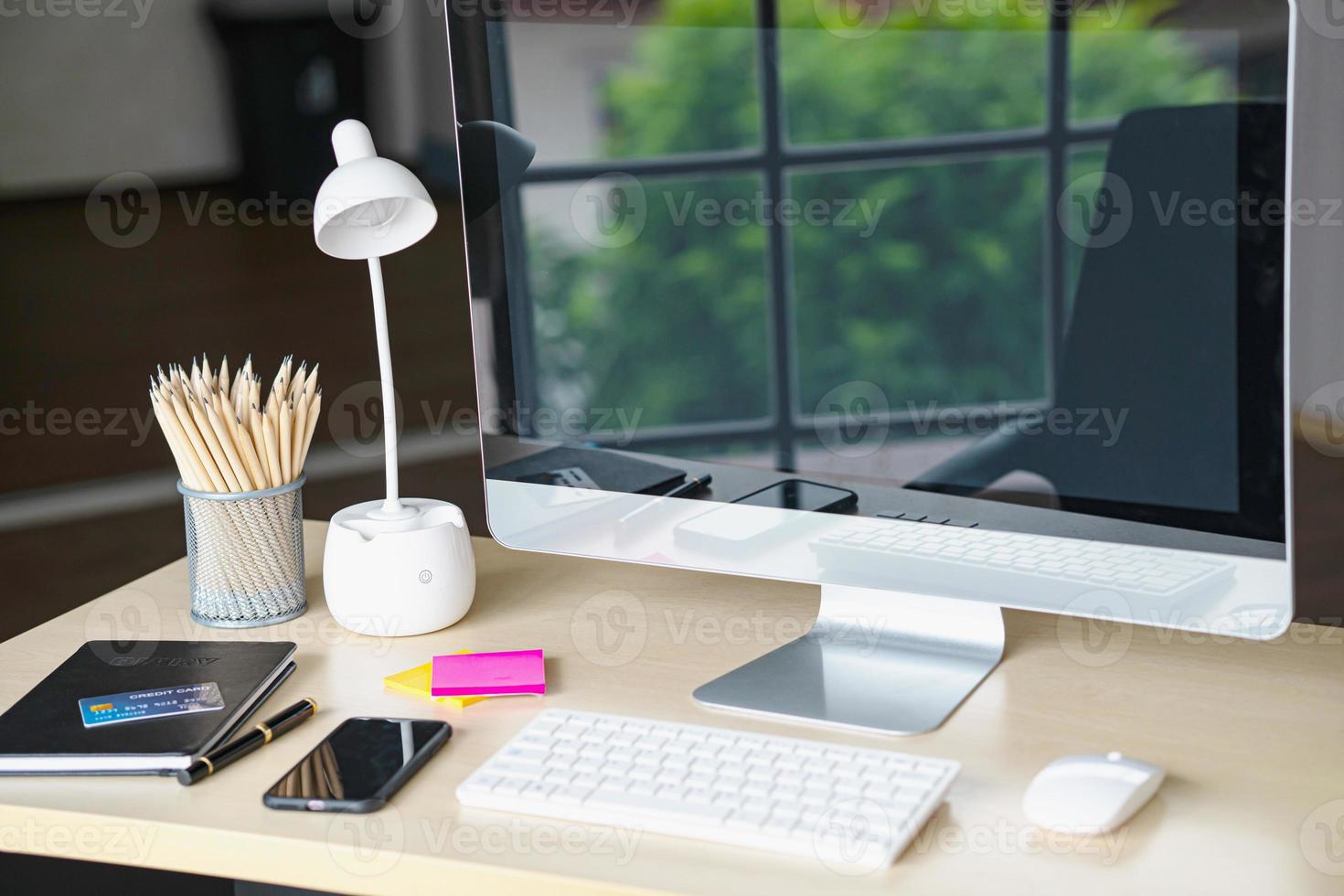 Business and workplace concept. Cup of hot coffee on work desk with computer keyboard Mobile and papers graphs working room. photo