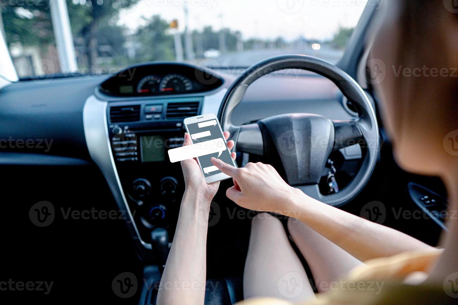 Young woman typing text on mobile smartphone.while driving a car photo