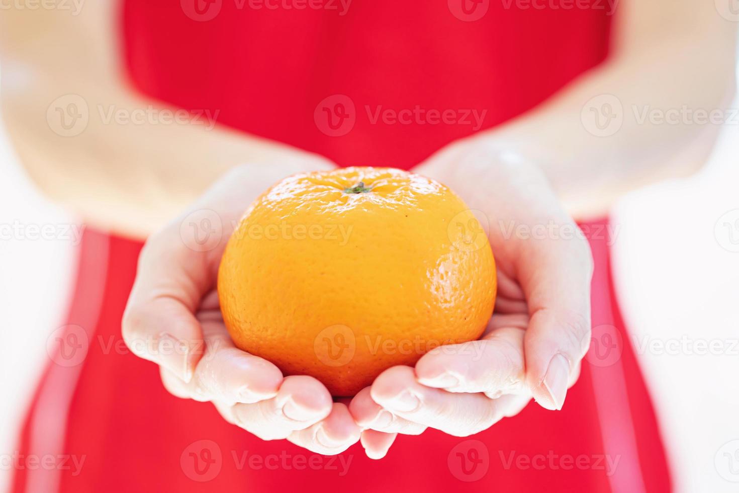 Asian girl in china traditional dress holding an orange and giving you a happy in Chinese New Year photo