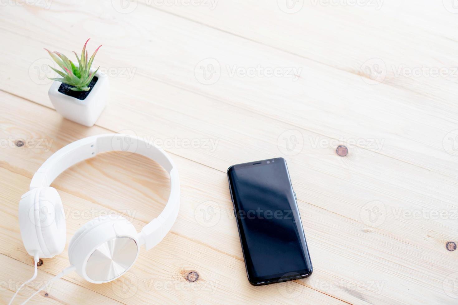 Smartphone and headphones on the table wood photo