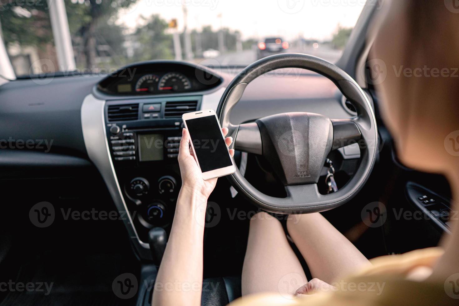 Young woman in car checking her smartphone while driving photo