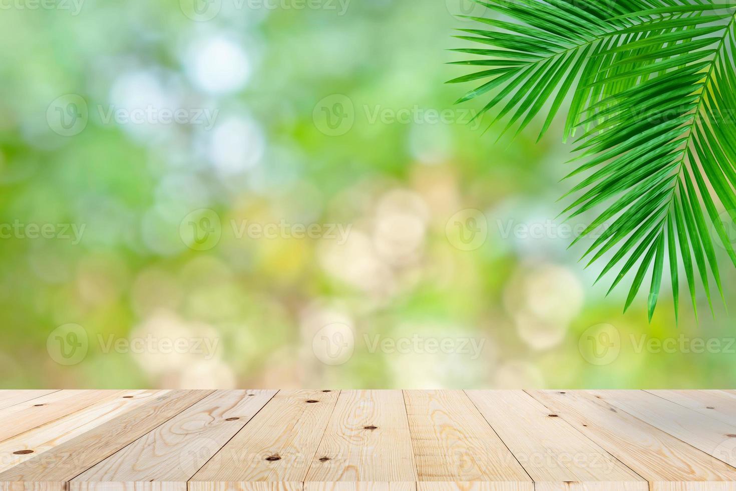 Empty wooden table top and green bokeh palm leaf photo