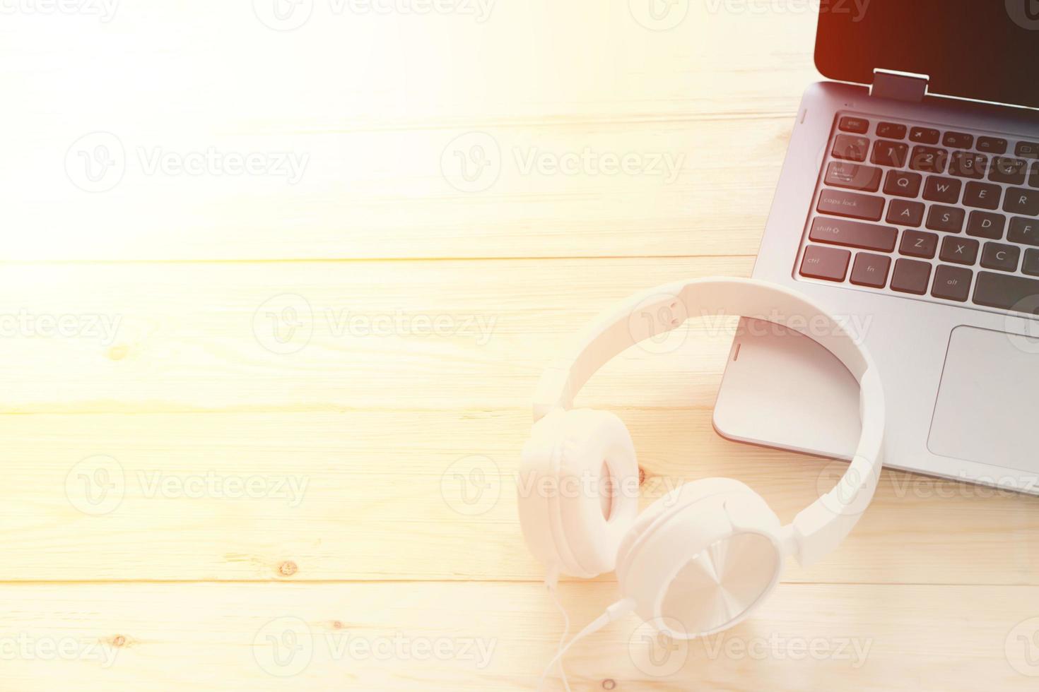 White headphone and laptop computer on wooden background photo