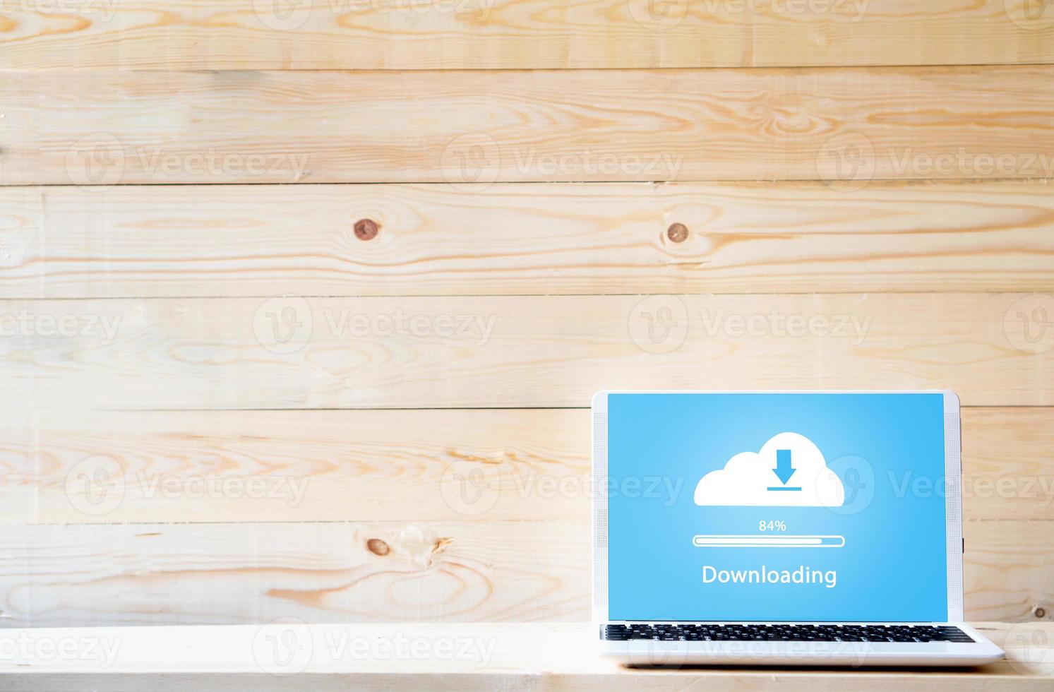 Cloud downloading on laptop  on wood table photo
