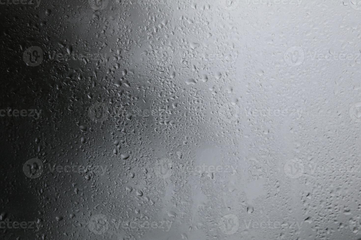 gotas de lluvia sobre un fondo negro gotas de agua sobre un fondo oscuro vidrio de protección contra la lluvia para los autos que caen en las tardes que entran las tormentas. foto