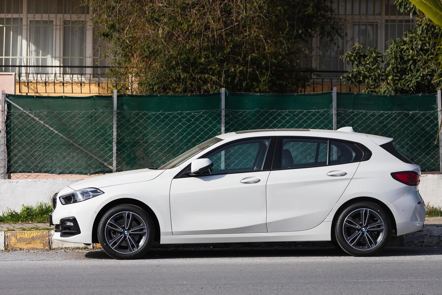 Side  Turkey  February 18 2022 white  BMW 1 series    is parked  on the street on a warm  autumn  day photo