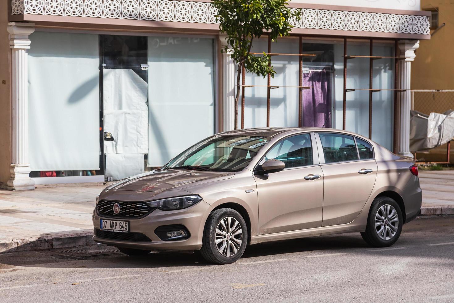 Side Turkey February  20, 2022 beige Fiat Egea   is parking  on the street on a  summer day against the backdrop of a   shops photo