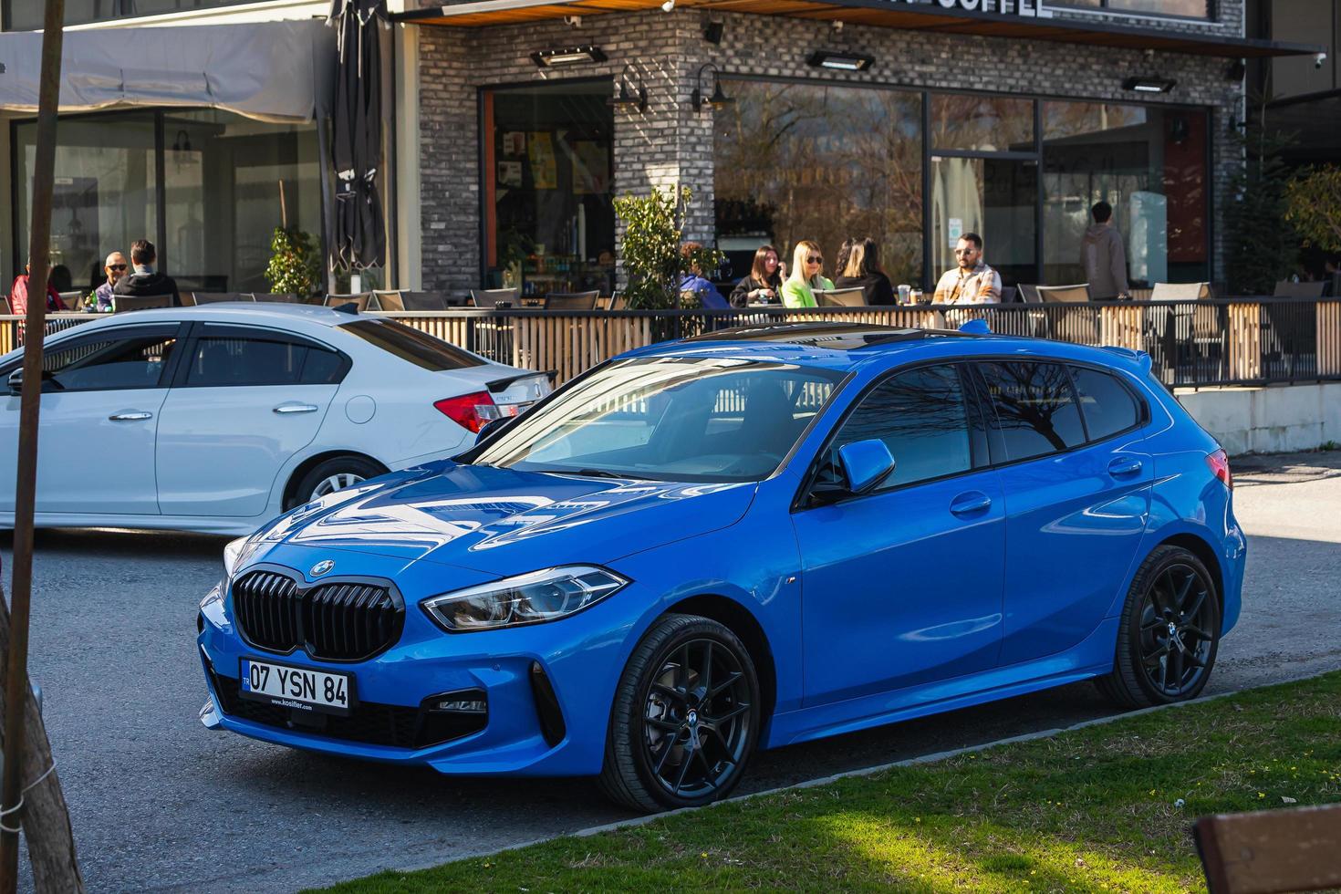 Side Turkey  March 01 2022 blue  BMW 1 series    is parked  on the street on a warm  autumn  day against the backdrop of a shops photo