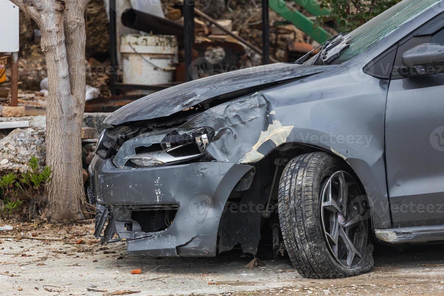 broken car after an accident. Close-up of a broken headlight, blown off wheel, dents on the fender and bumper photo