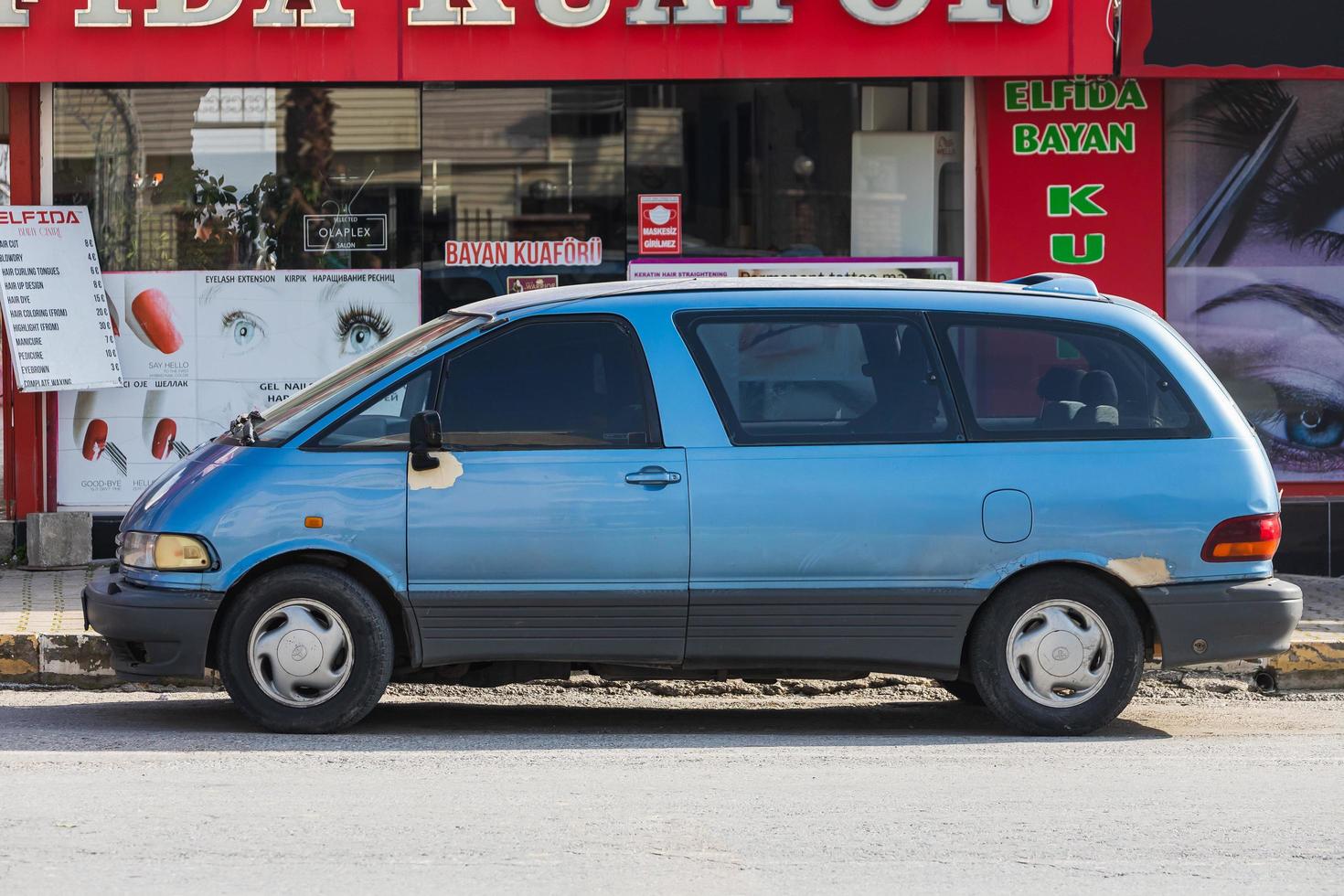 Side  Turkey  February 18 2022  blue Toyota Previa   is parked  on the street on a warm day against the backdrop of a buildung,   park, fence, shops photo