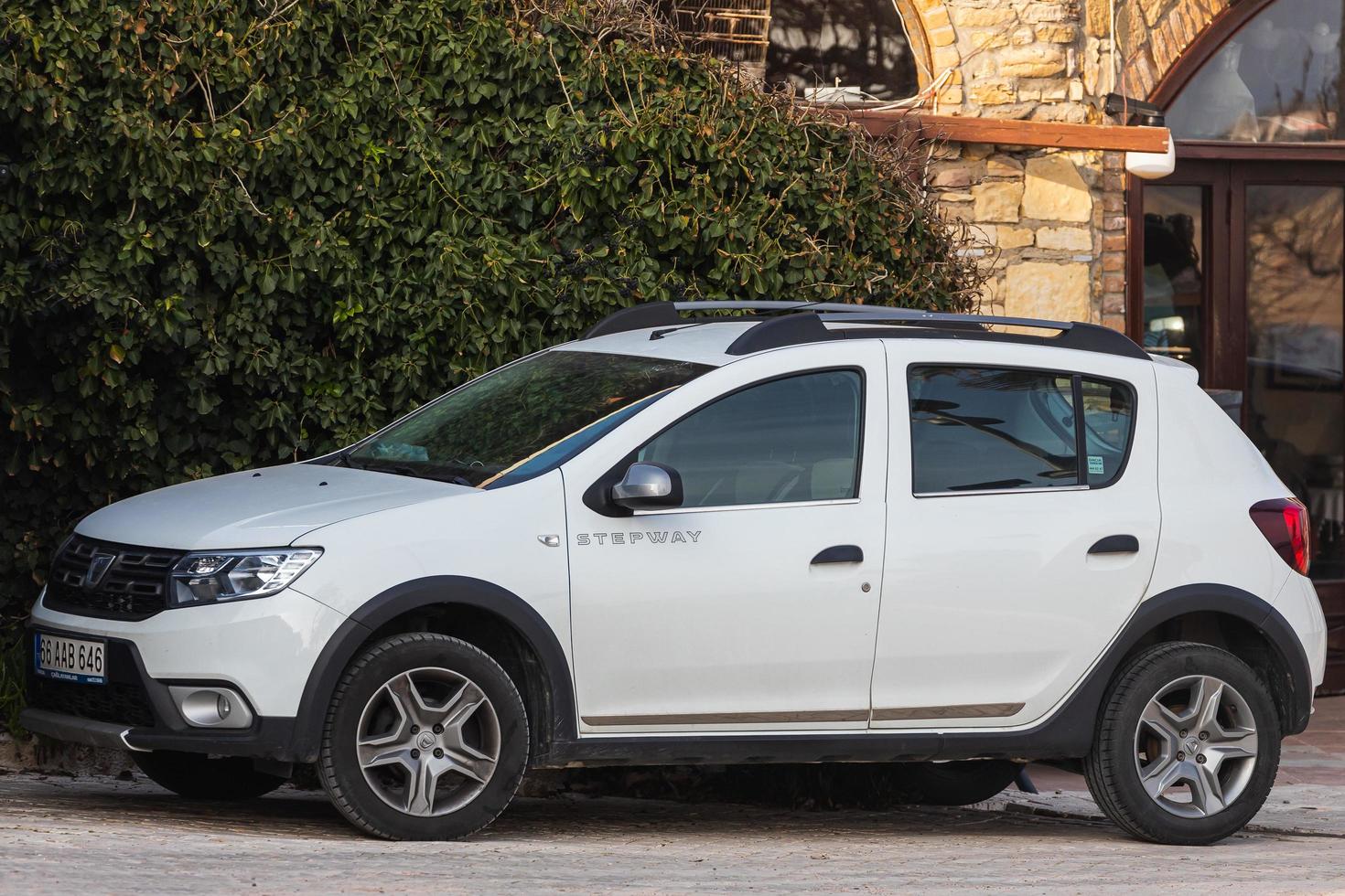 Side  Turkey  February 18 2022  white  Dacia Sandero Stepway  is parked  on the street on a warm  day against the garden photo