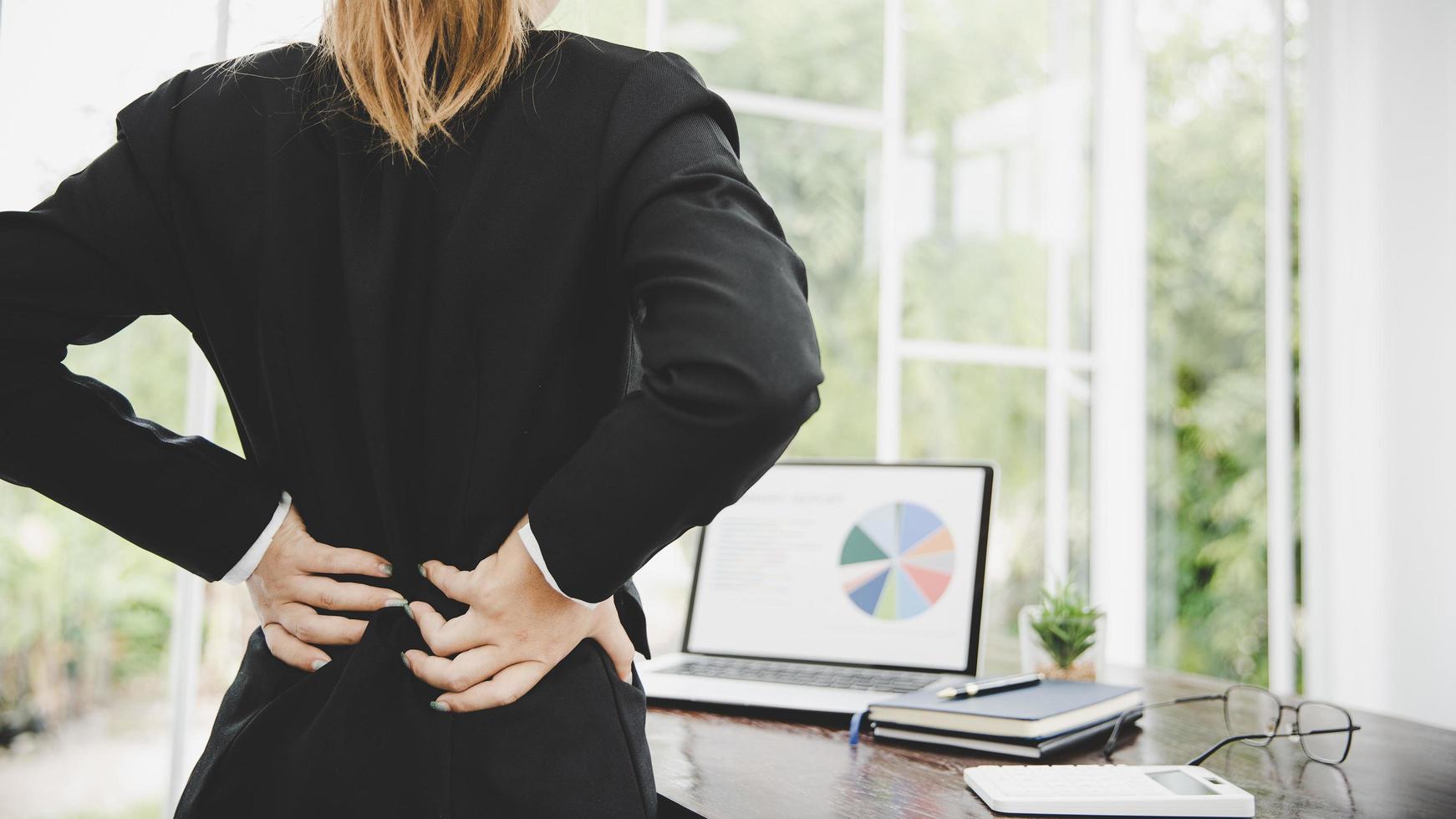 Young business woman at the office with terrible back pain photo