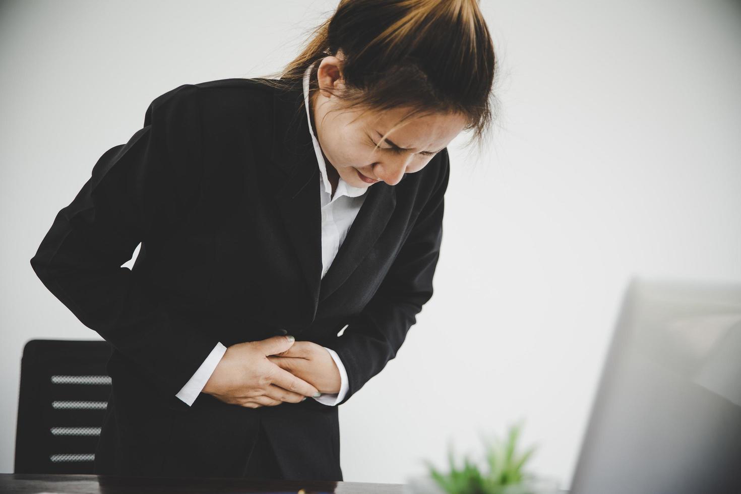 young business woman suffering from stomach pain photo