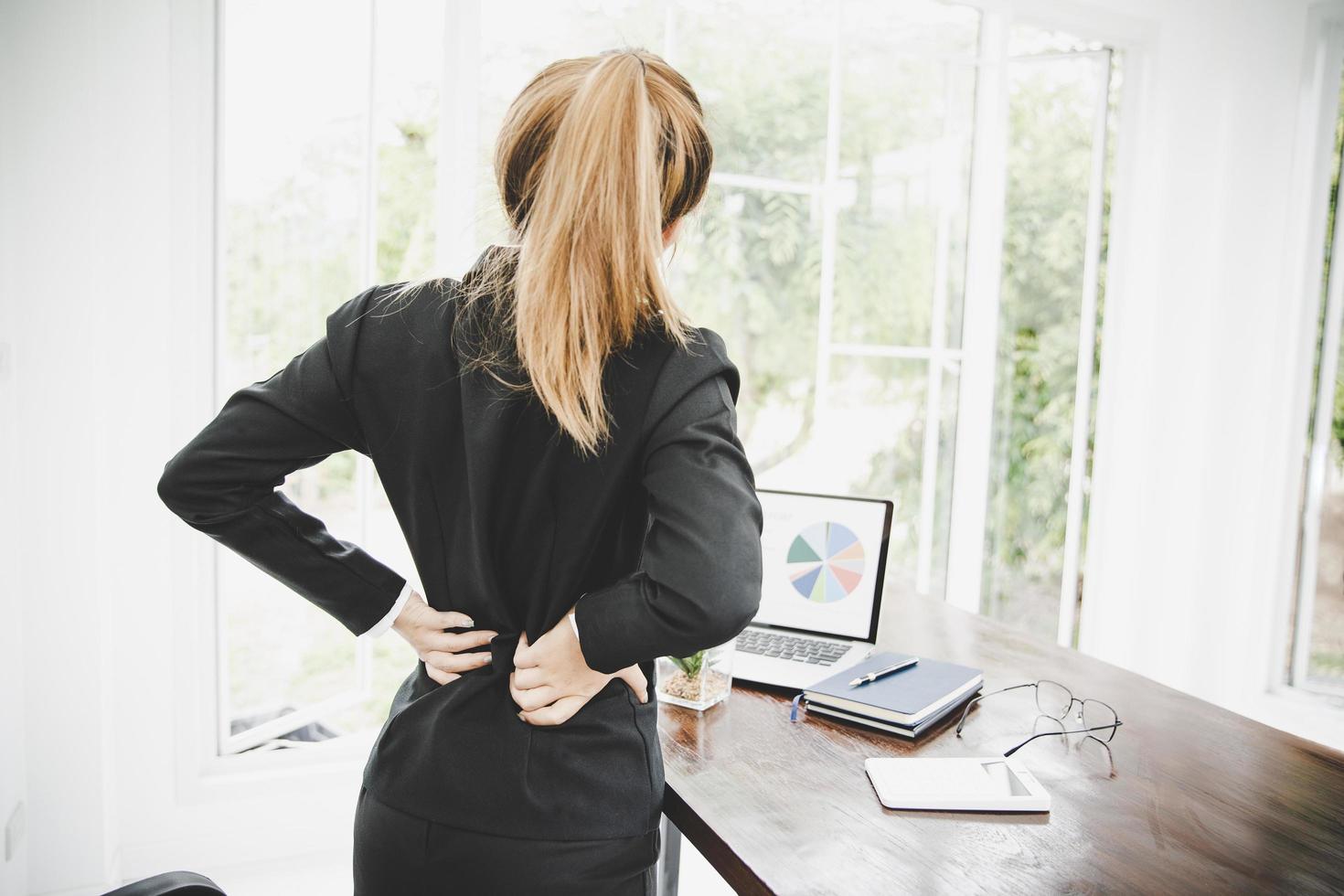 joven mujer de negocios en la oficina con terrible dolor de espalda foto