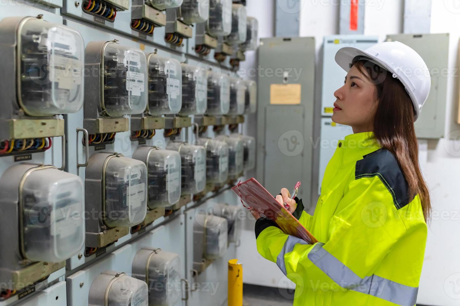 mujer ingeniera eléctrica revisando el voltaje en el gabinete de distribución de energía en la sala de control, mantenimiento preventivo anual, electricista de tailandia trabajando en la empresa foto