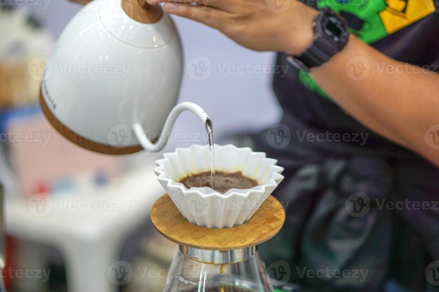 Closeup hands of Barista making and pouring fresh dip coffee from the kettle for customer in a coffee shop. photo