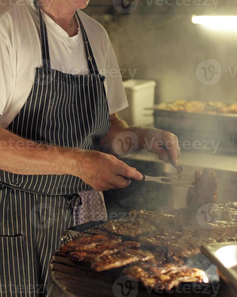 Man wearing an apron working the bbq grill photo