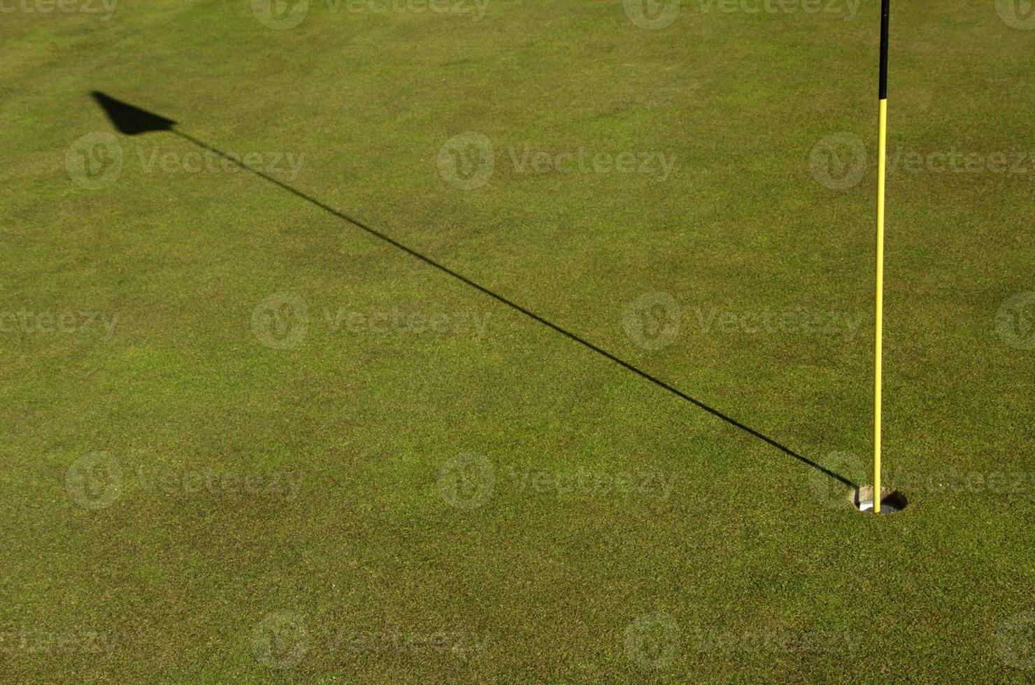 Golf course with flag stick on a sunny day photo