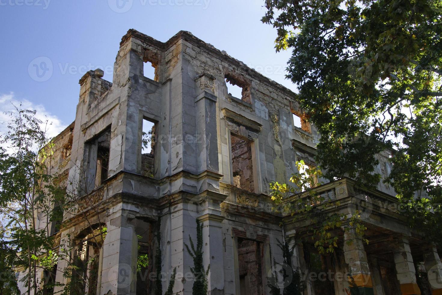 Remains of the war in Mostar, Bosnia and Herzegovina - Ruin without a roof with trees growing inside of it photo