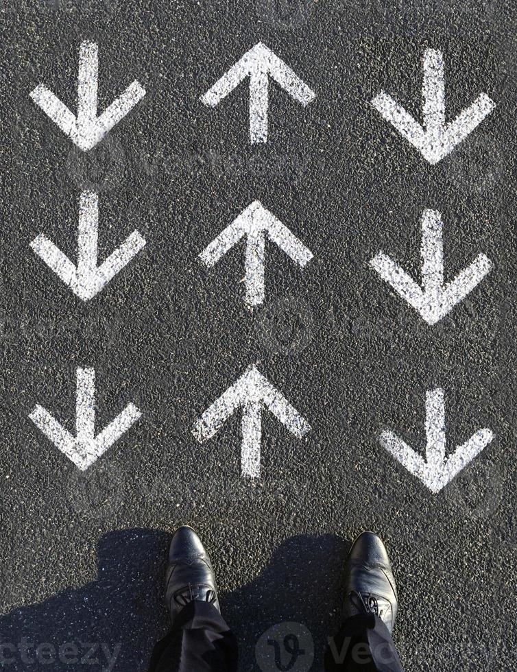 Finding your own way - Man standing in front of arrow symbols leading forward and backwards photo