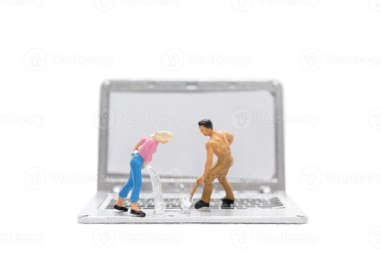 Miniature people cleaning laptop computer on white background photo