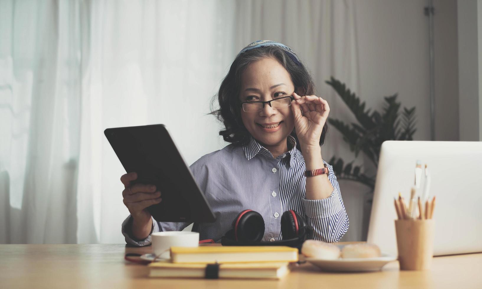 Middle age senior woman sitting at the table at home working using computer laptop with a happy face standing and smiling with a confident smile showing teeth photo