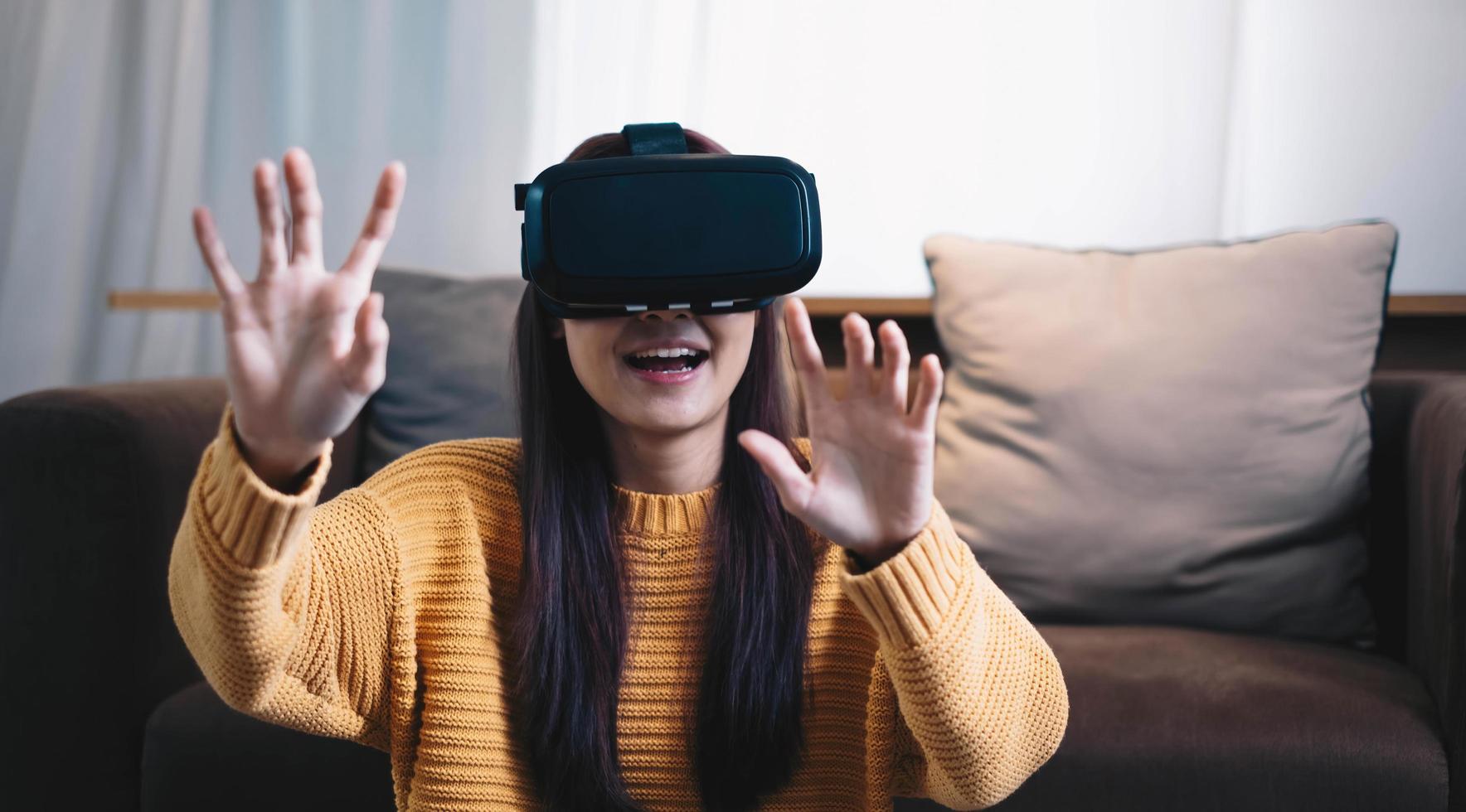 mujer asiática juega juego vr para entretener en casa, mujer asiática alegre en casa de vacaciones. mujer feliz jugando el concepto de tecnología metaverse vr. foto