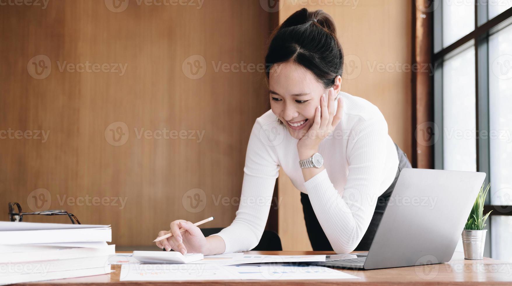 Portrait of Young Asian woman hand freelancer is working her job on computer tablet in modern office. Doing accounting analysis report real estate investment data, Financial and tax systems concept. photo