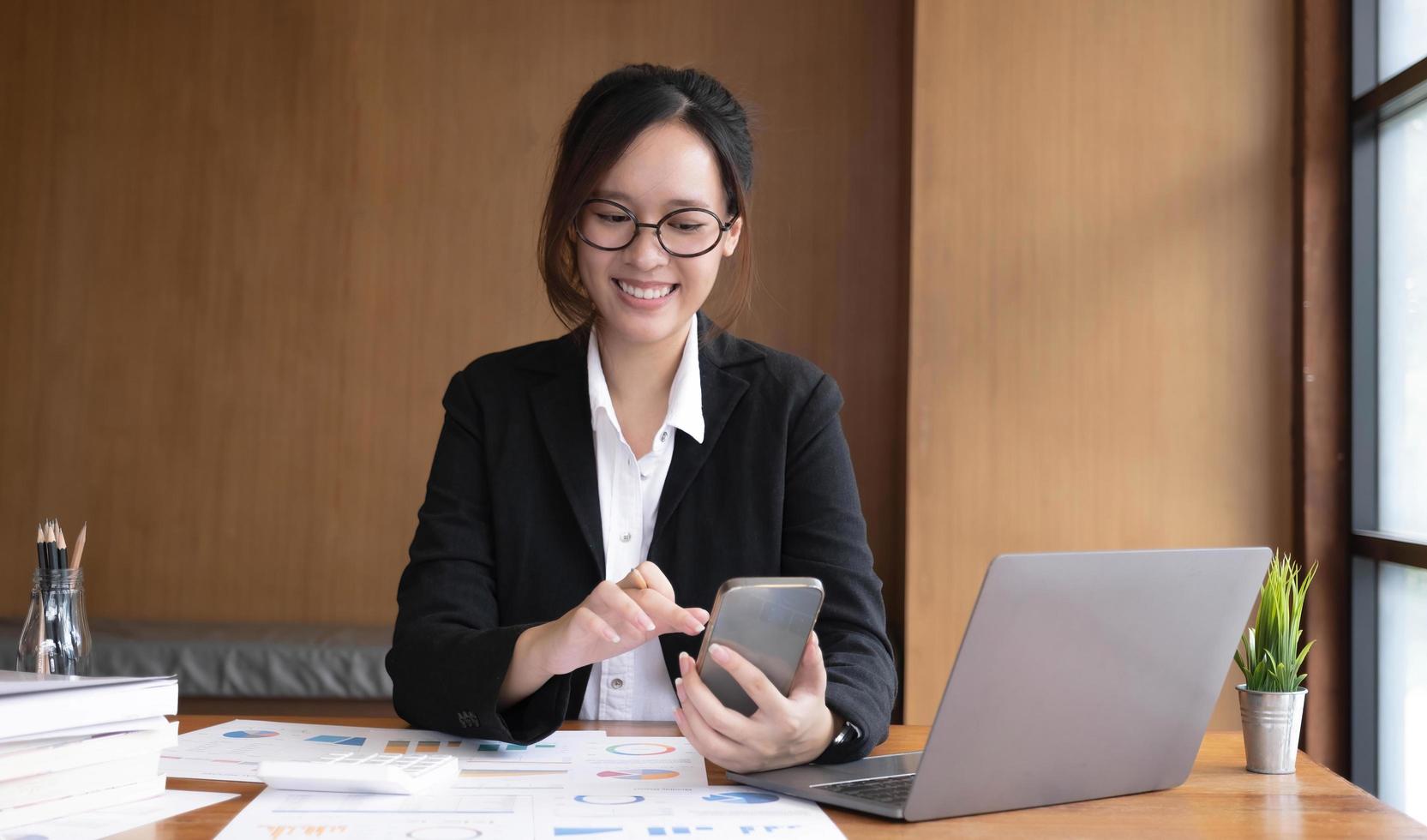 Young asian businesswoman beautiful charming smiling and using on mobile phone in the office. photo