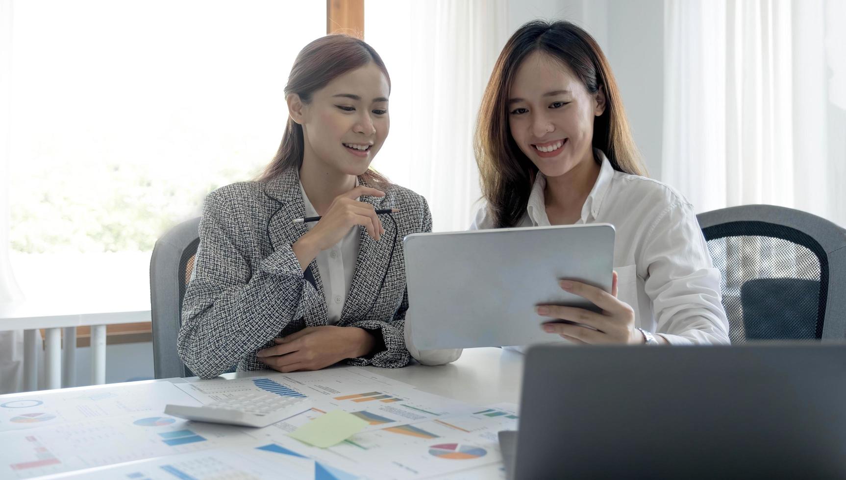 Two beautiful young asian businesswoman working together using digital tablet at office. photo