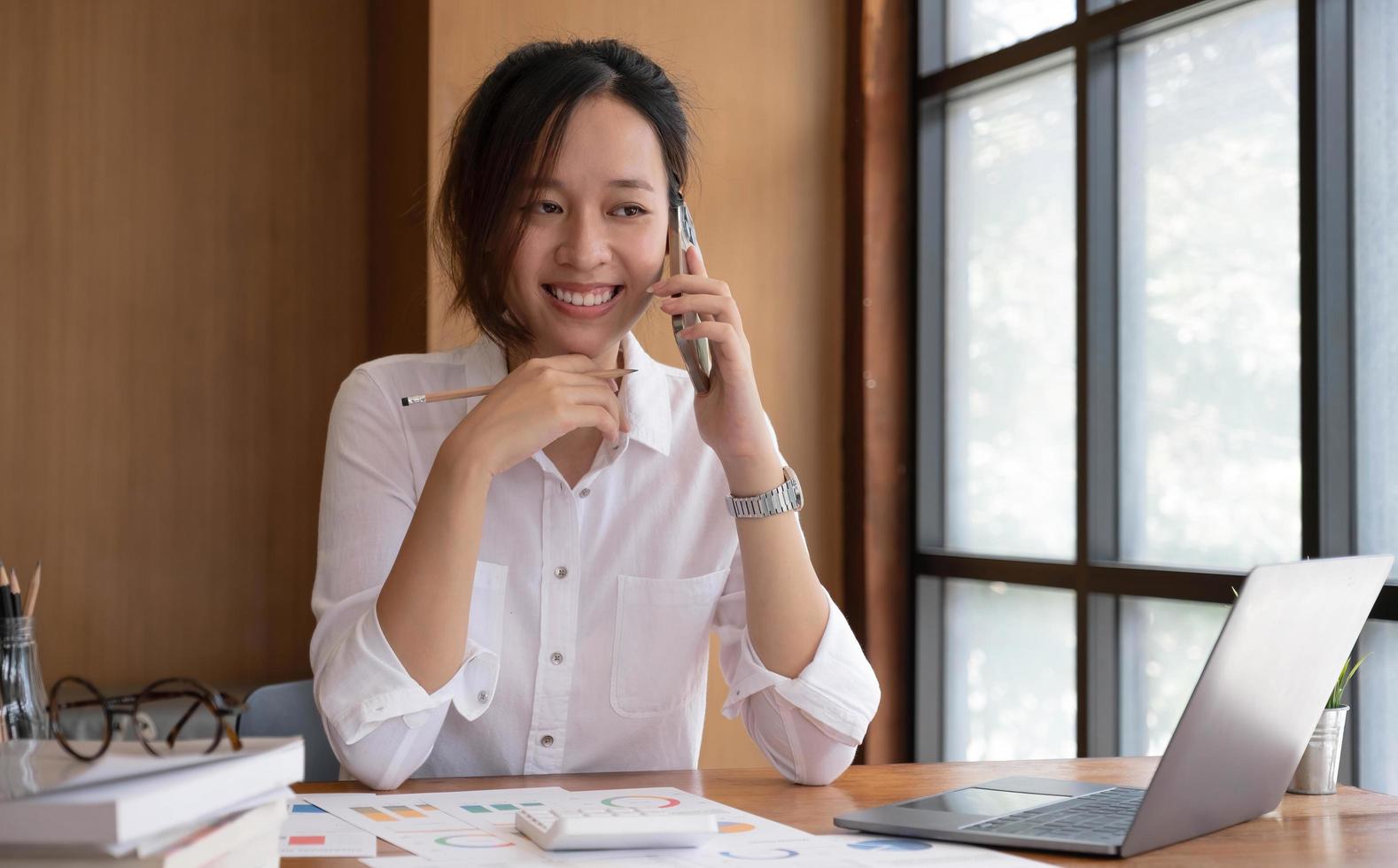 Asian business woman have the joy of talking on the phone, laptop and tablet on the office desk. photo