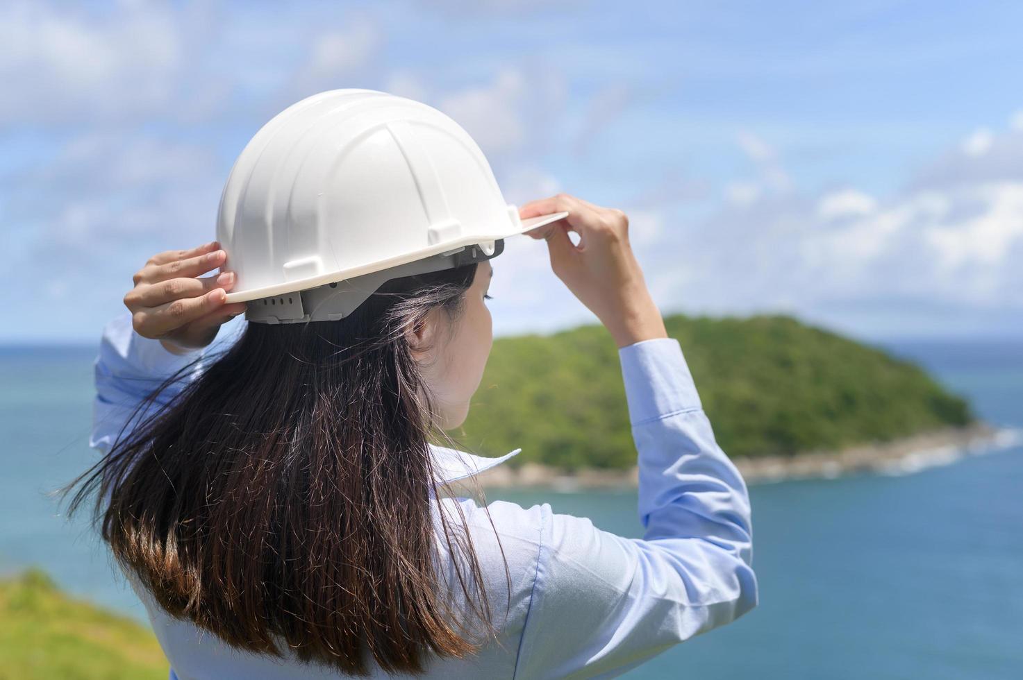 Female engineer working on the seaside wearing a protective helmet photo