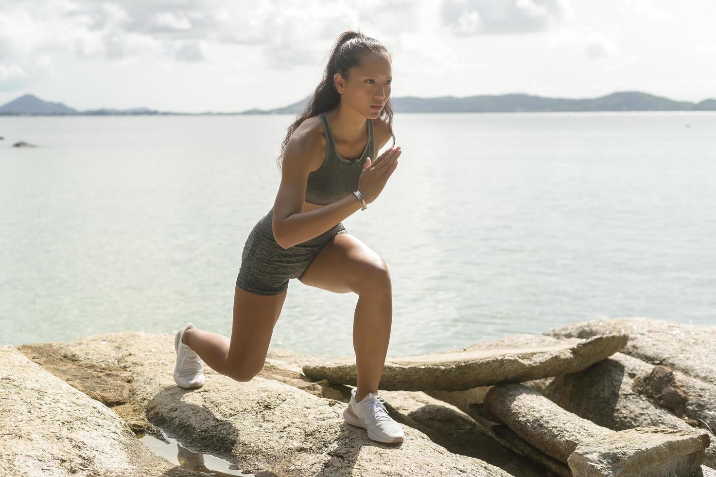 A Beautiful fit woman in sportswear exercising on seaside mountain peak, Health and Travel concept. photo