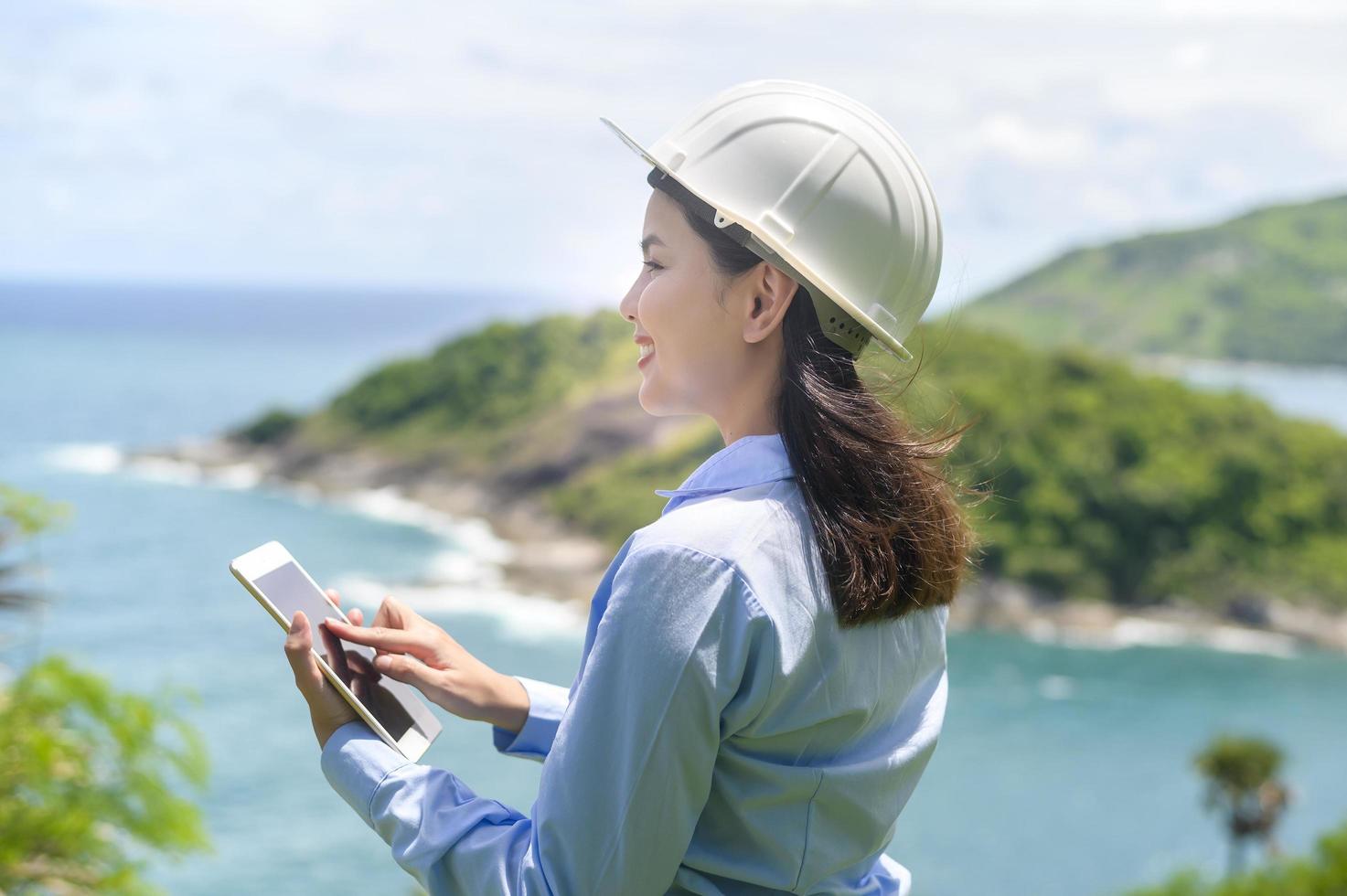 mujer ingeniera trabajando en la playa con un casco protector foto