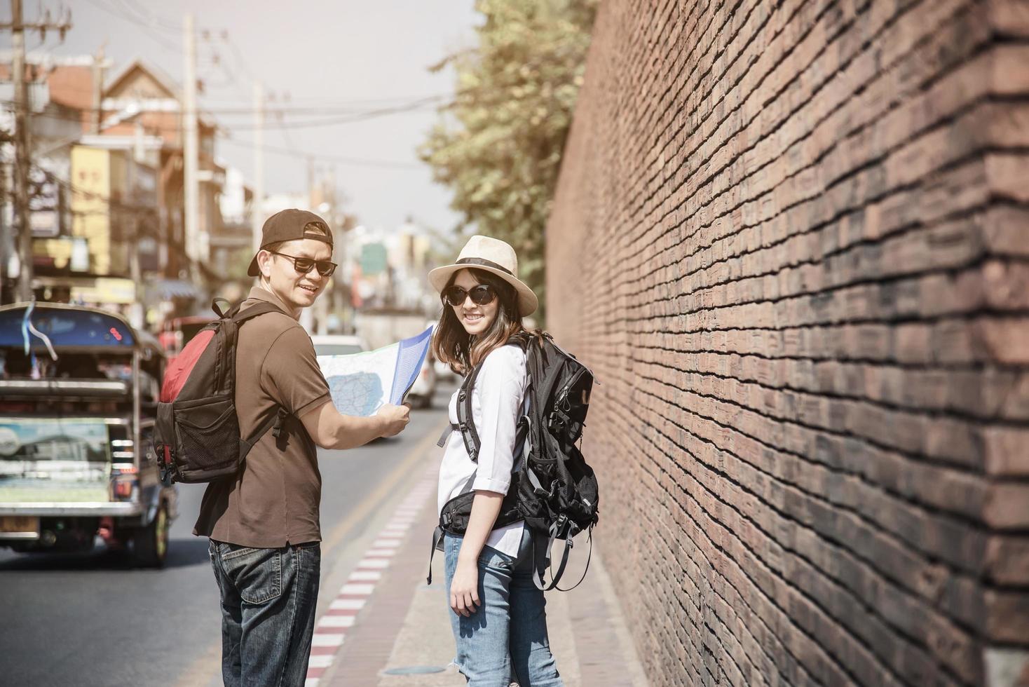 mochila asiática pareja turista sosteniendo un mapa de la ciudad cruzando la carretera - gente de viaje concepto de estilo de vida de vacaciones foto