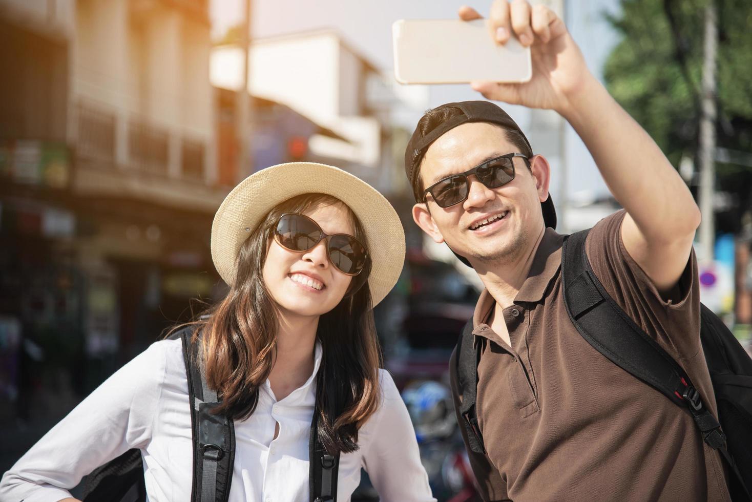 Asian backpack couple tourist holding city map crossing the road - travel people vacation lifestyle concept photo
