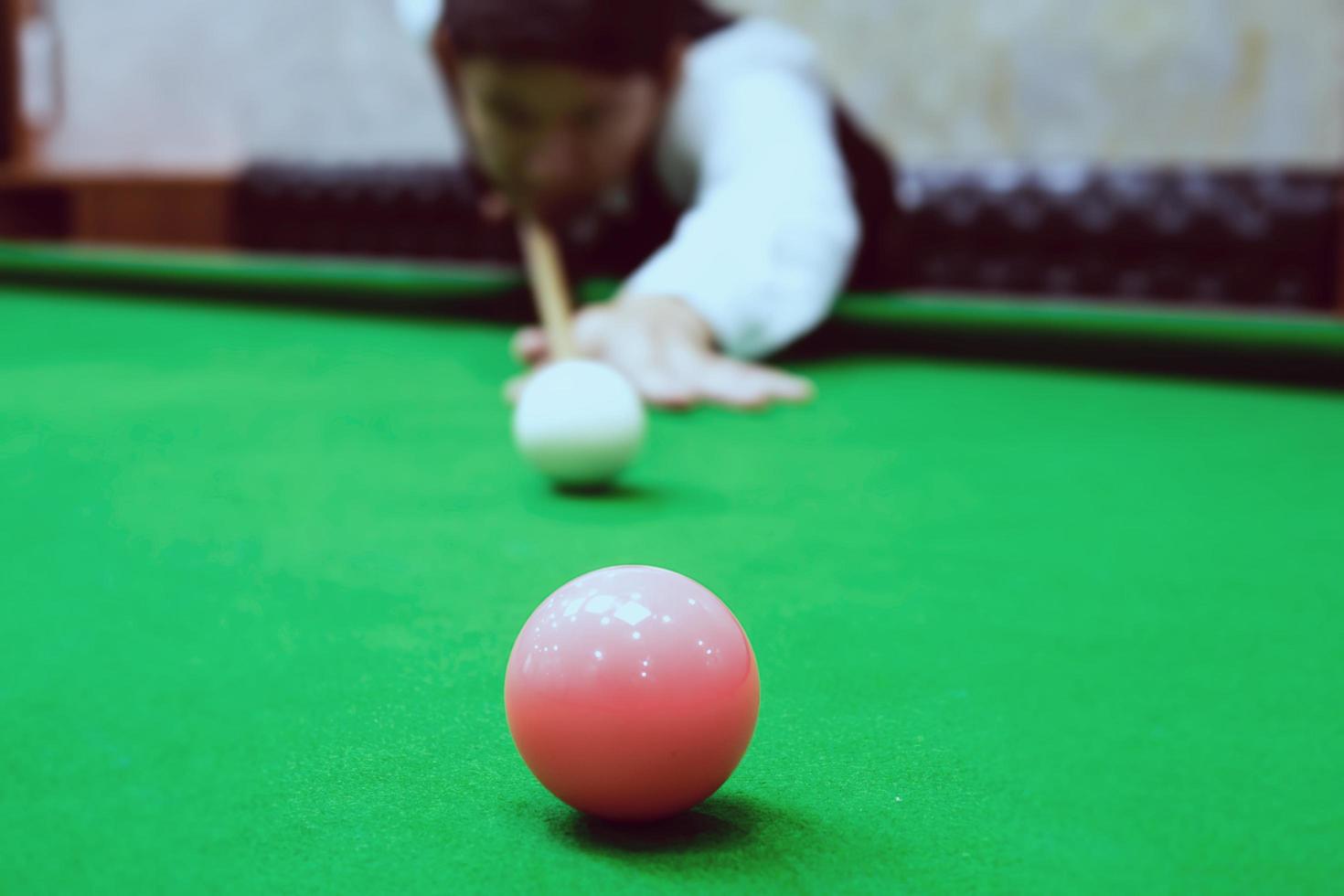 hombre asiático jugando billar apuntando su taco a una bola blanca - jugador de billar en concepto de partido de competición foto