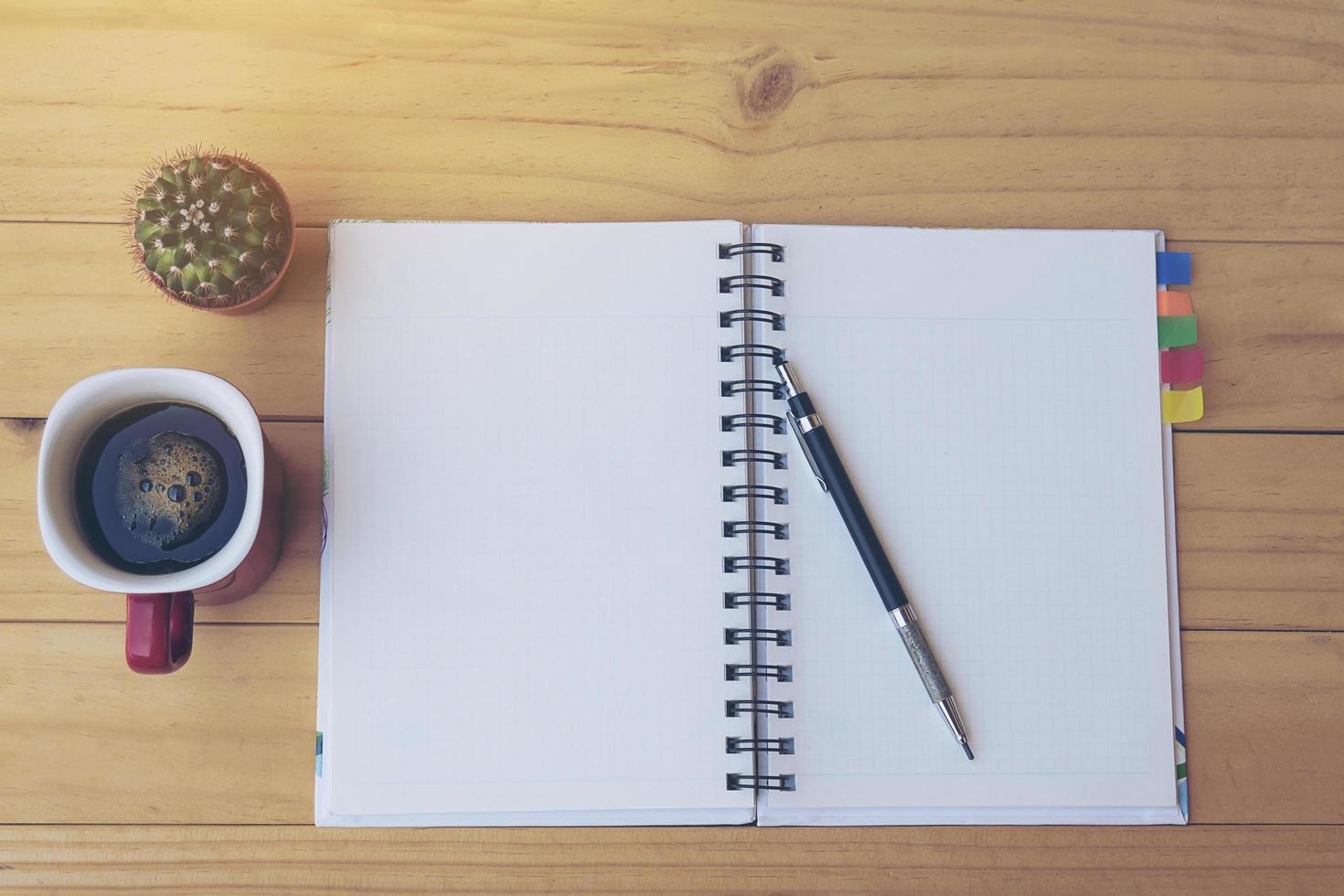 Top view note book on wooden table with coffee cup and small cactus pot photo