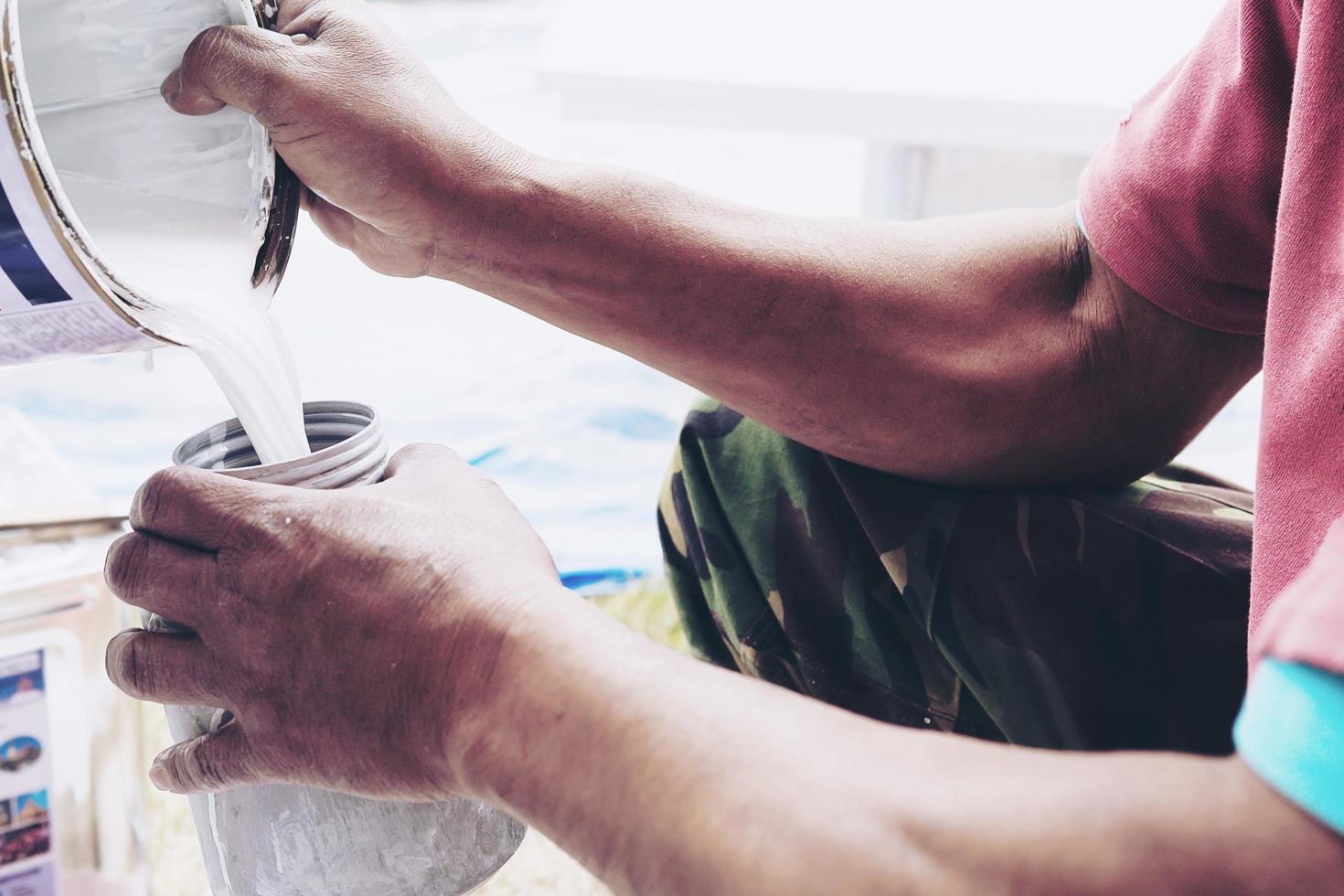 Man working with liquid colour preparation for spray paint machine to colour furniture in new house installation process - workman painting furniture onsite concept photo