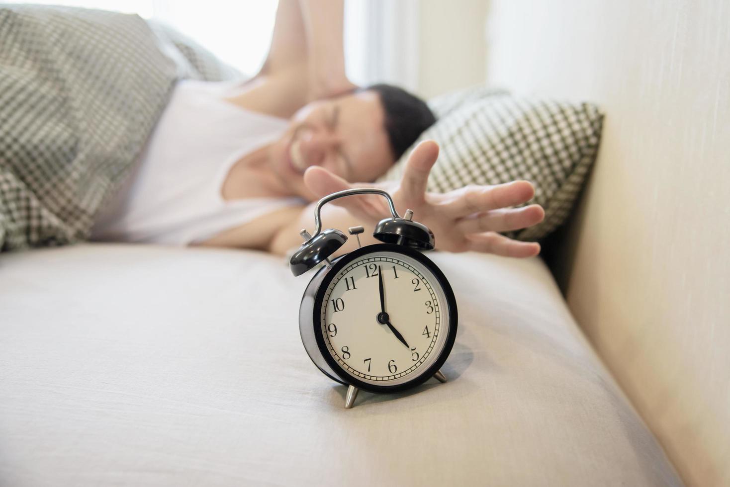 Sleepy man holding the alarm clock in the morning with late wake up - every day life at home concept photo