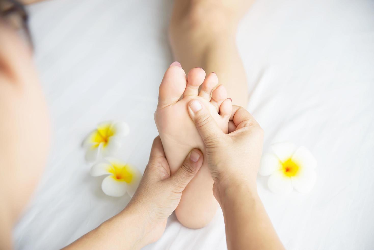 Woman receiving foot massage service from masseuse close up at hand and foot - relax in foot massage therapy service concept photo