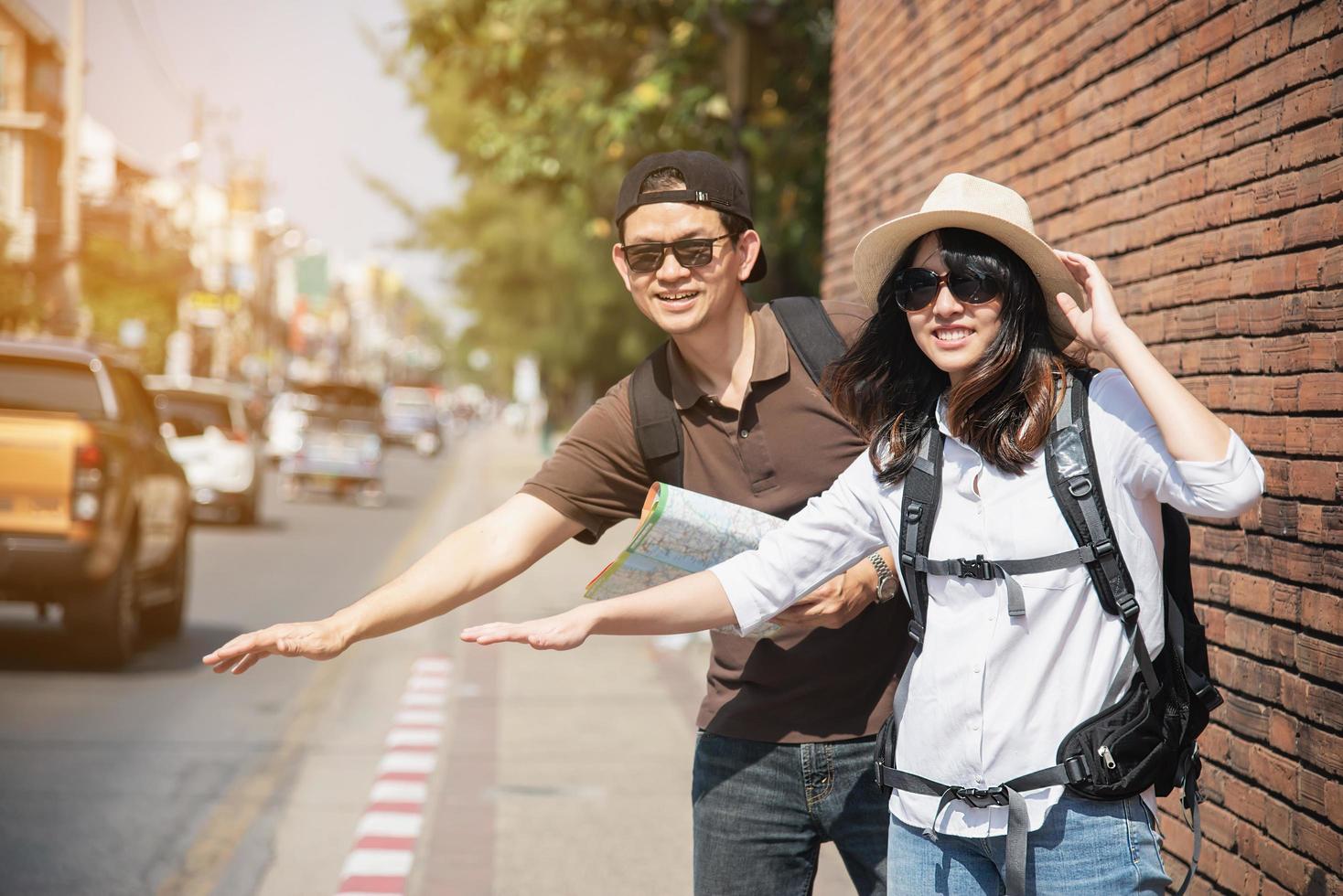 Asian backpack couple tourist holding city map crossing the road - travel people vacation lifestyle concept photo