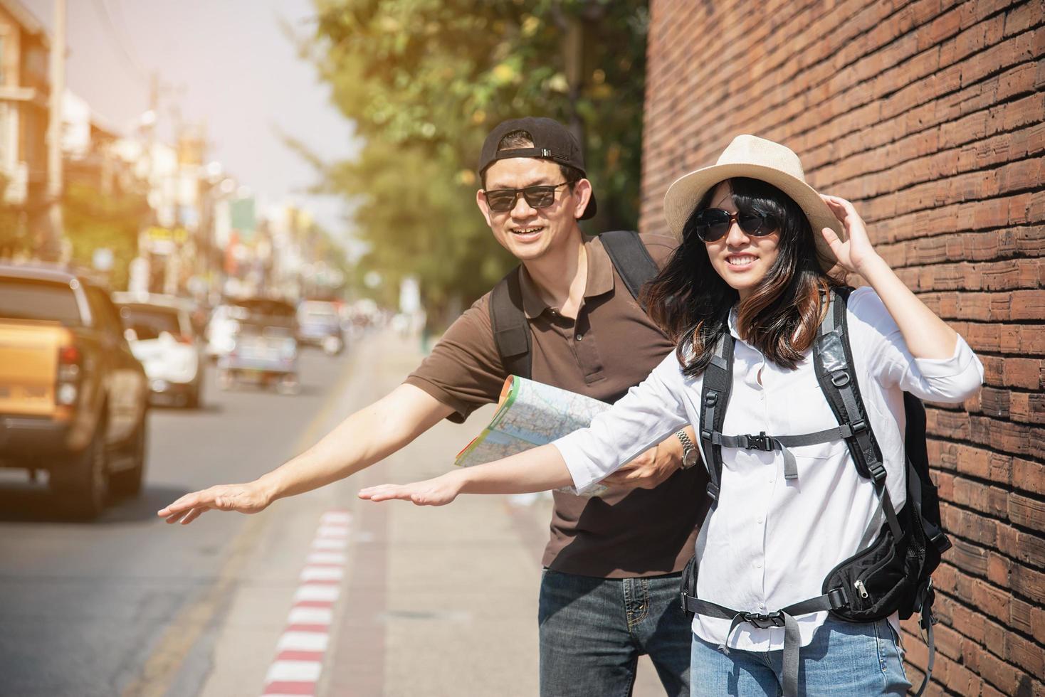 mochila asiática pareja turista sosteniendo un mapa de la ciudad cruzando la carretera - gente de viaje concepto de estilo de vida de vacaciones foto