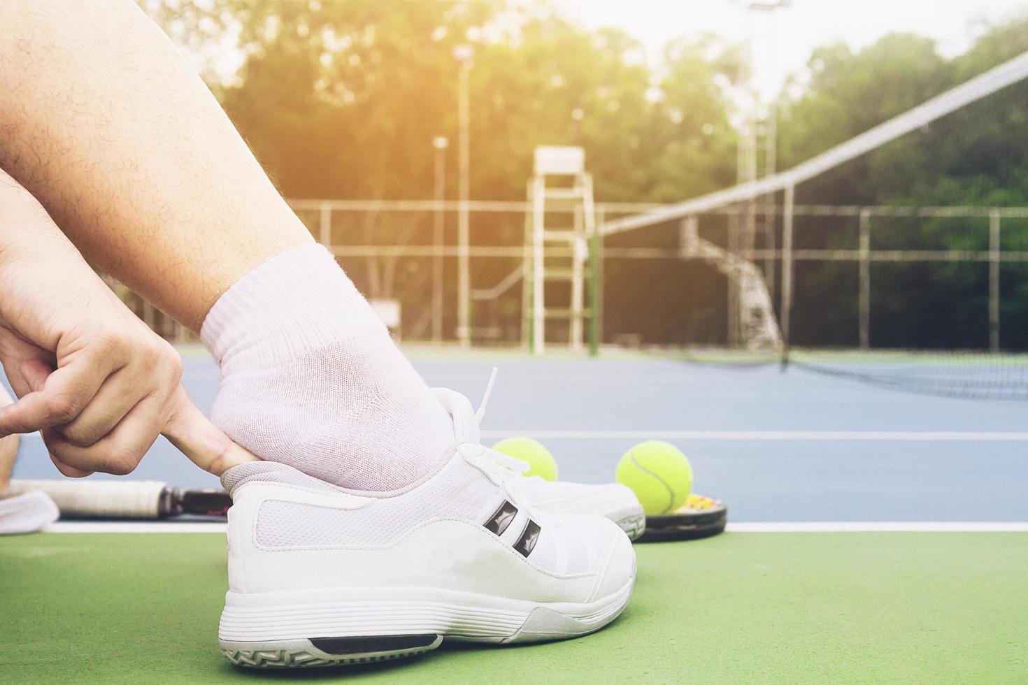 Tennis player is putting shoe before the match in tennis hard court photo