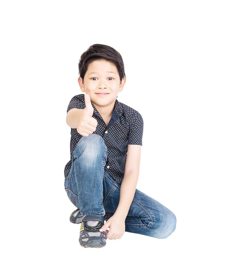 Asian boy showing thumbs up while sitting isolated over white photo